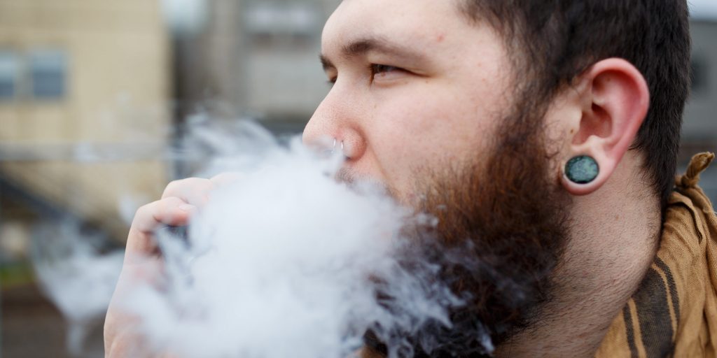 man blowing vape cloud