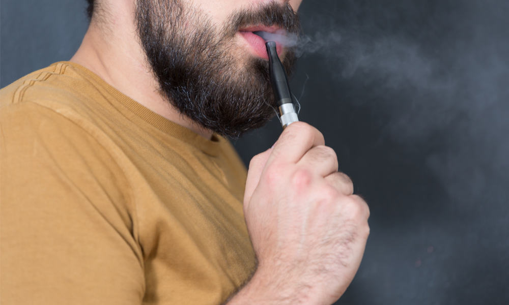 Bearded man vaping blue lotus vape pen
