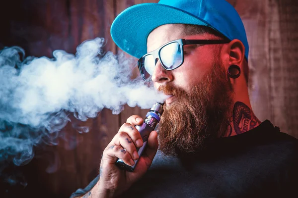 Guy using a sub ohm vape showing white smoke blowing from his face.