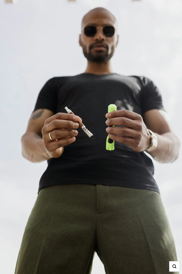 Dry herb vaporizer held by a guy wearing shades pointing it downards.