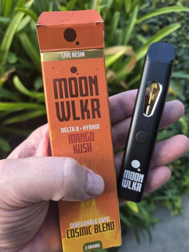 MOONWLKR Delta 8 2G Disposable Mango Kush held by a person with their hands showing the orange box and the vape device itself.