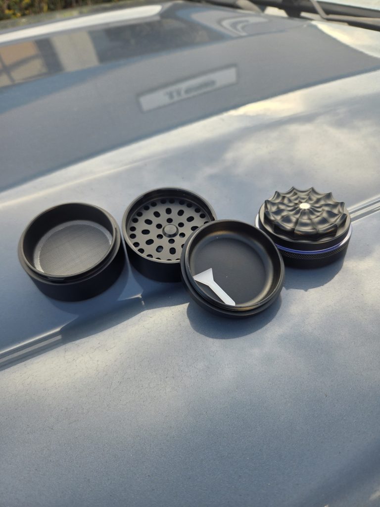 WNC Toothless Grinder displayed on top of a hood showing the interior of the top and bottom parts, displaying four pieces in all.