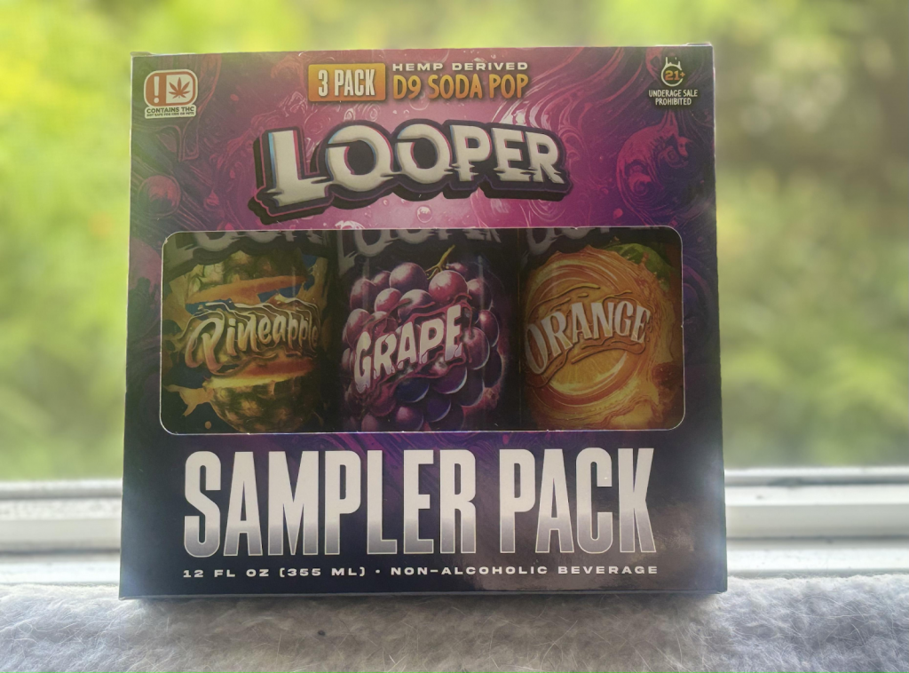 Three cans of Looper D9 Soda Pop displayed inside of a sampler pack showing three flavors: Pineapple, Grape, and Orange.