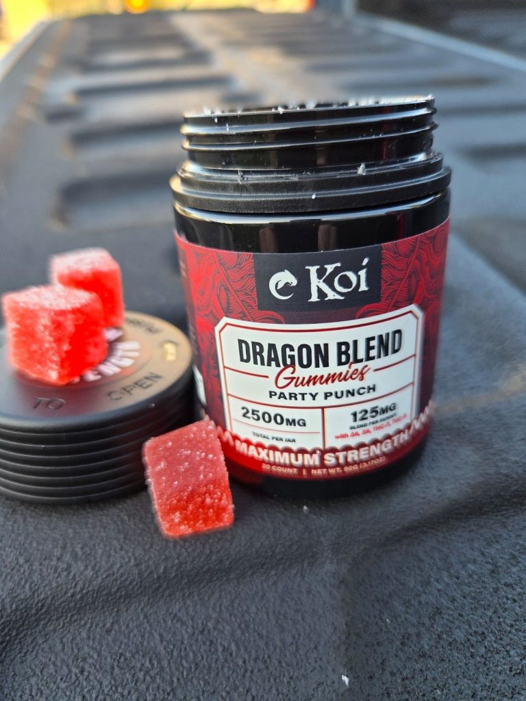 Koi CBD Dragon Blend Gummies displayed on a white background showing the red and black container with two red gummies on top of the cap.