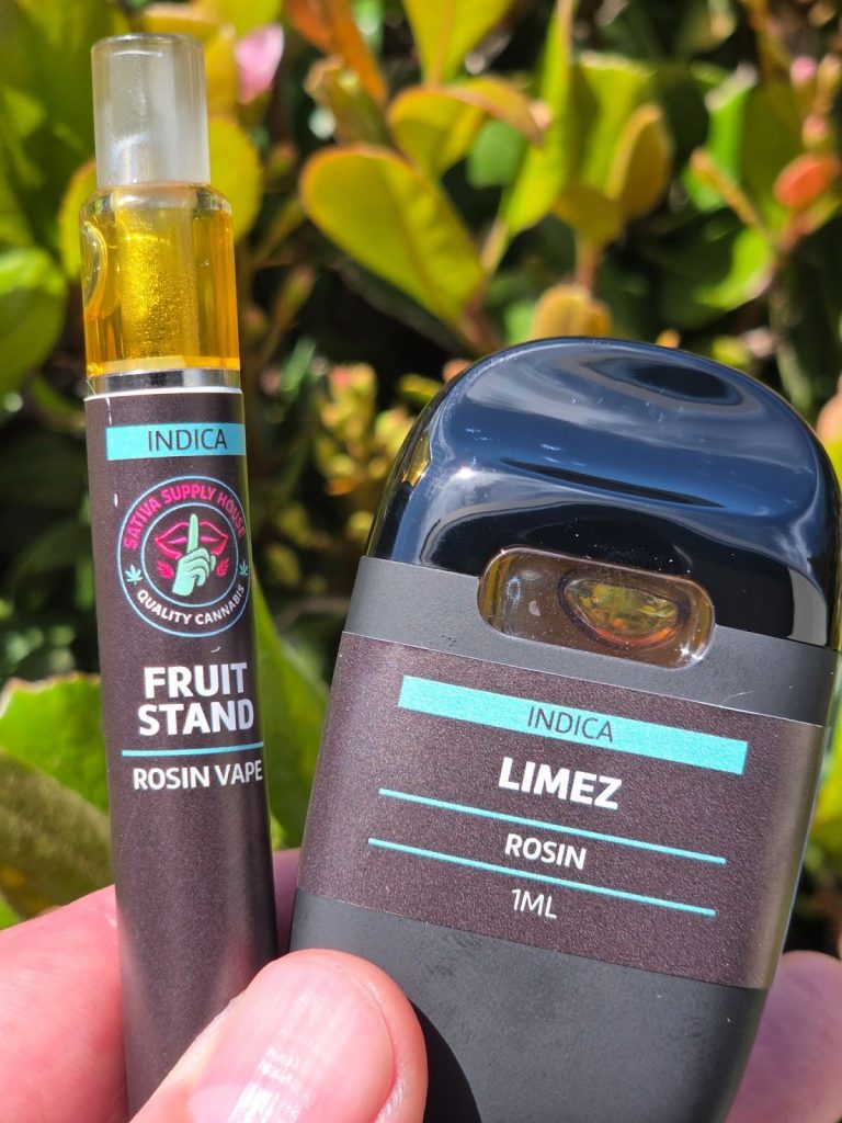 Sativa Supply House Live Rosin Vape Cart displayed in front of a  garden being held by someone.