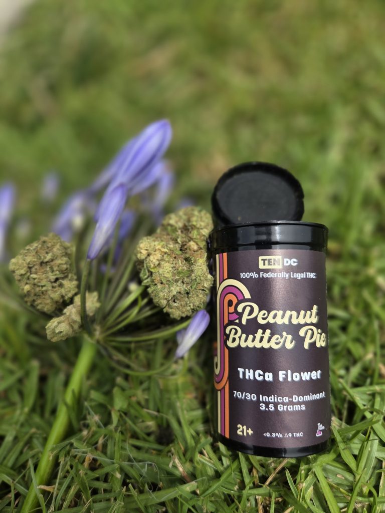 10DC Double Peanut Butter Pie displayed on top of a grass patch with the actual hemp flower attached to a stem.