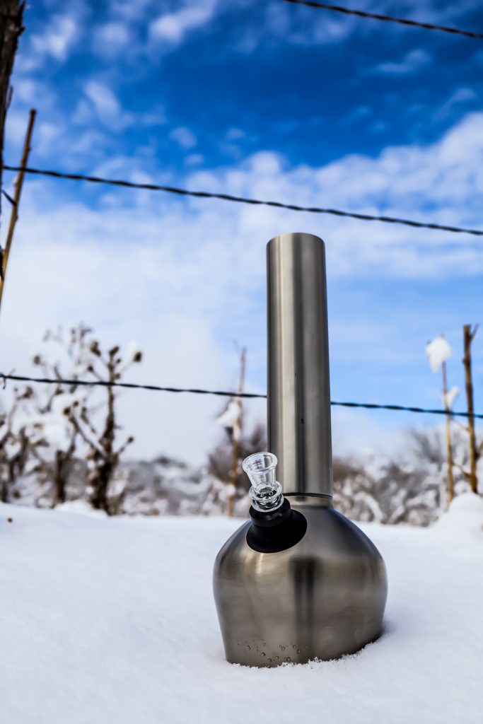 Best pipe for smoking outdoors placed on top of a pile of snow with the sky and two barbed wires in the background.