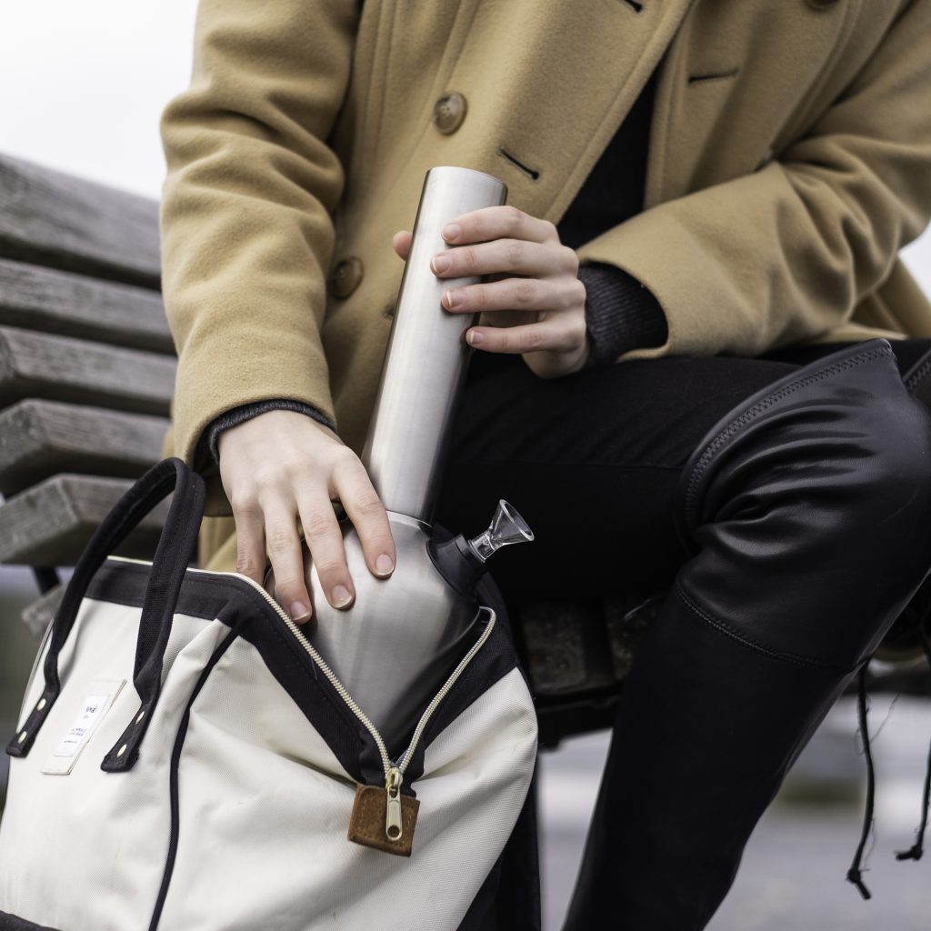 Best pipe for smoking outdoors held by someone that is putting it inside a bag seated on a bench.