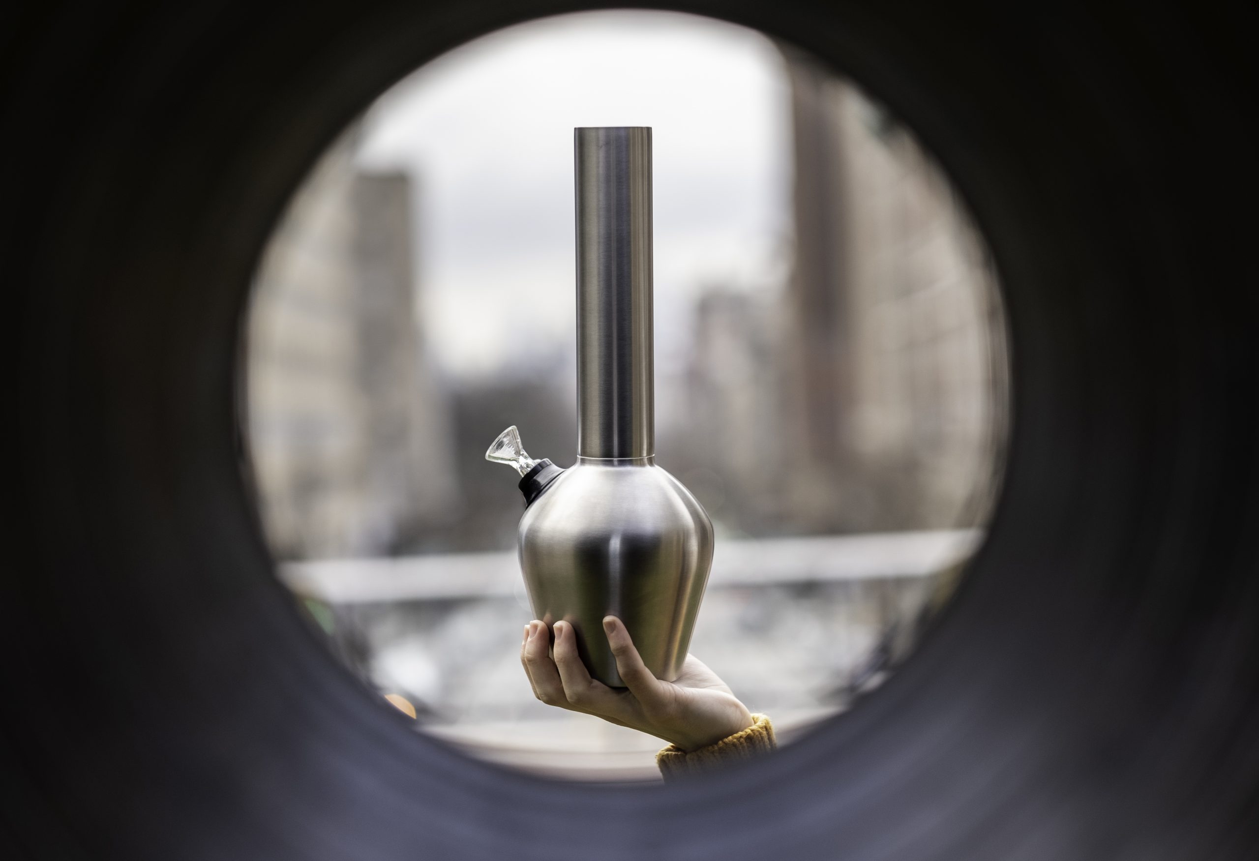 Best pipe for smoking outdoors held by someone in front of a pipe with the city in the background.