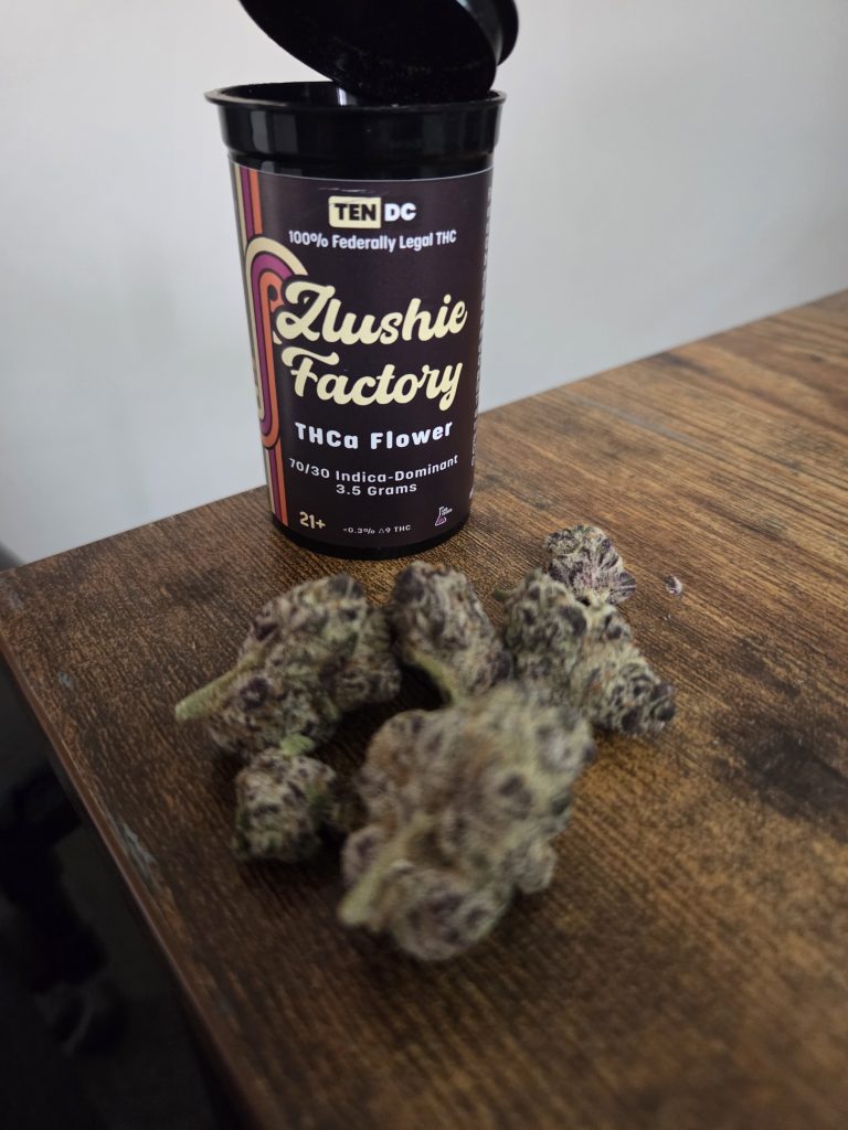 Jar 10DC Zlushie Factory displayed with the actual buds underneath it on top of a wooden table.