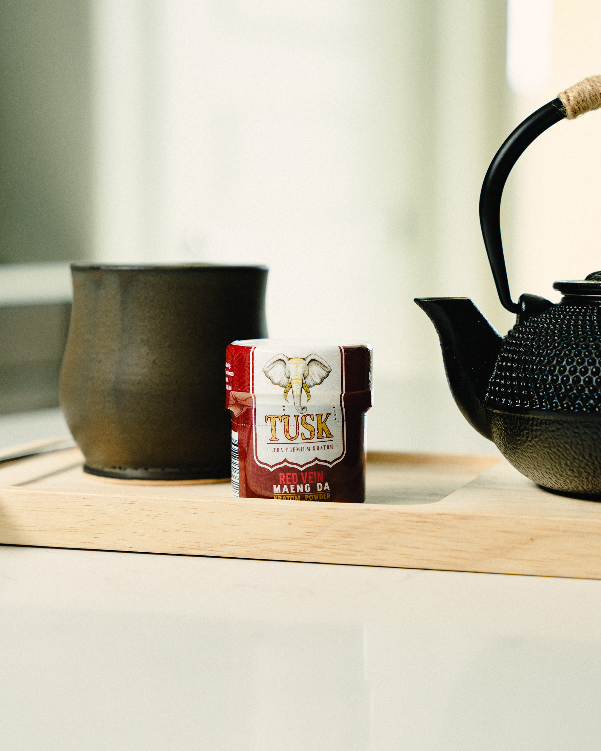 Kratom for sleep displayed on a kitchen counter and container with a kettle and pourer.