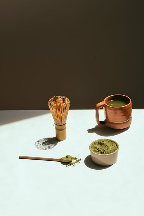 Kratom for anxiety displayed on top of a white table with spoon, cup, and brush mixer.
