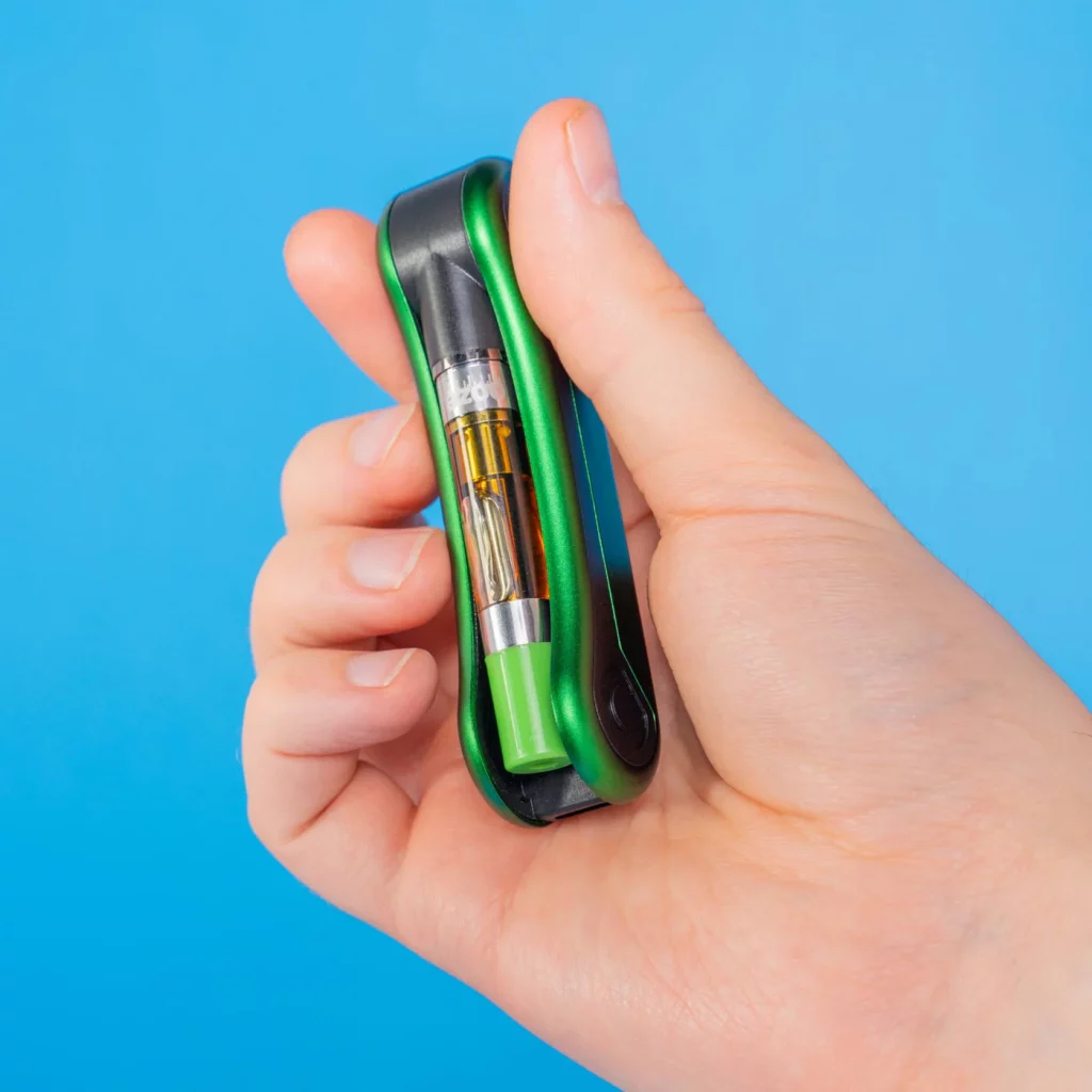 Hinge Flick 510 Thread Battery – 210 mAh – Green Drip displayed being held by a person to show different sides of it.