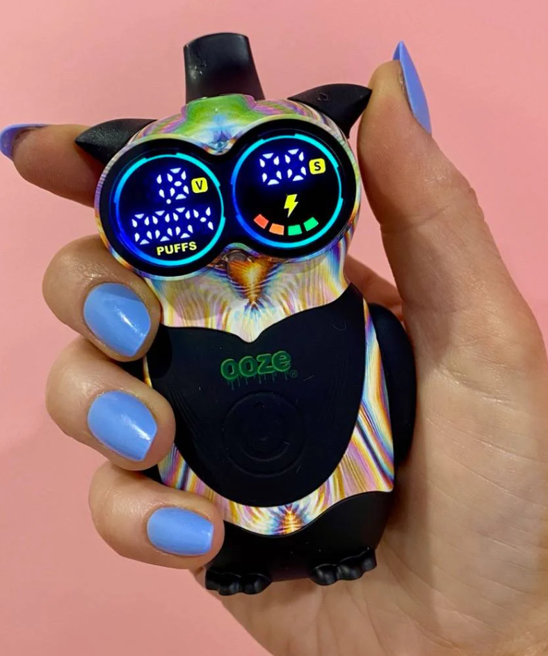 Ooze Hoot Character Vape – 650 mAh - Glitch being held by a woman's hand in front of a pink background.