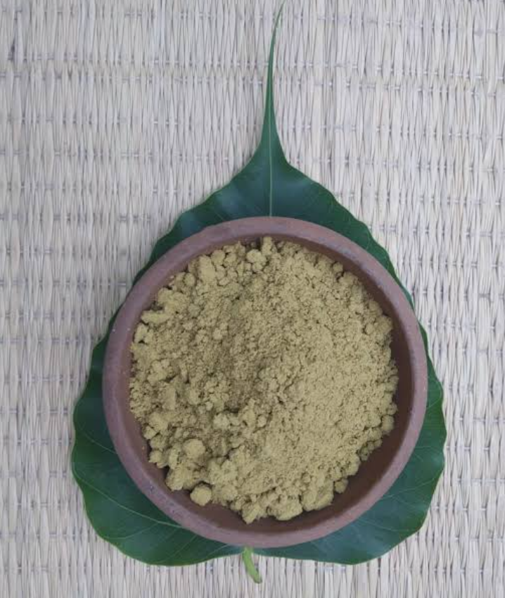 Kratom and Caffeine mixture being prepared showing a green kratom powder poured on a bowl on top of a kratom leaf.