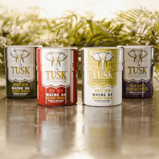 Kratom tea shown by Tusk kratom products displayed along each other in front of a bushy background on top of a marble floor.