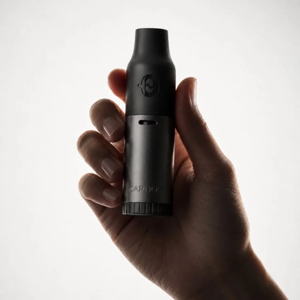 Quitting vape now demonstrated by a man holding a CAPNOS pressurized air inhaler displayed in front of a white background.