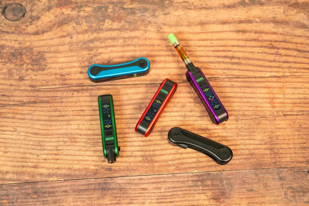 Ooze Hinge Flick 510 Thread Battery – 210 mAh – Sapphire Blue displayed with other product variations of its kind on top of a wooden flooring.
