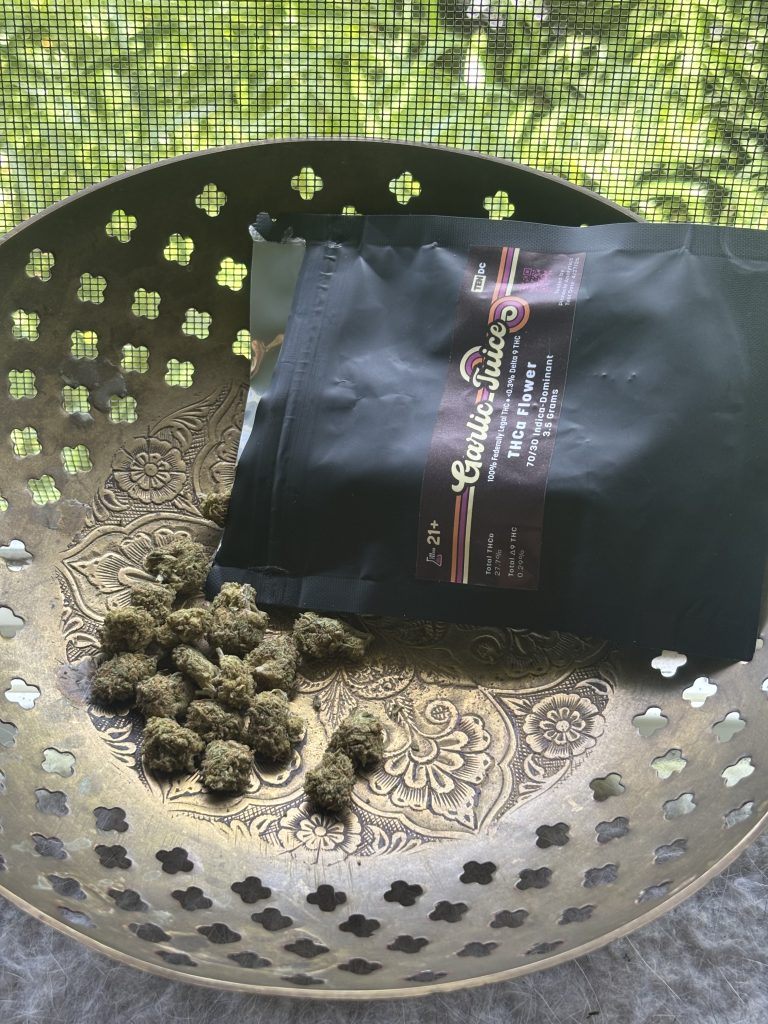 10DC Garlic Juice pack displayed on top of a bronze dotted bowl on top of a screen showing a grassy background.