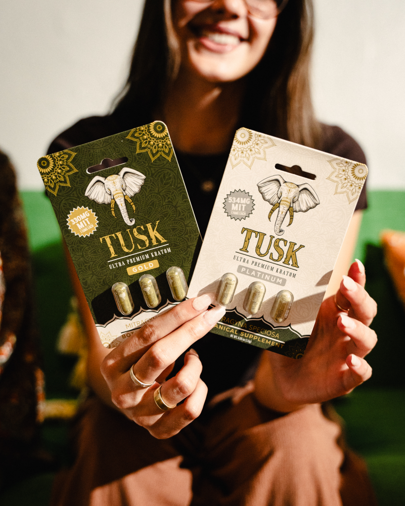 Single-serve kratom capsules being held by a smiling woman showing the Tusk Kratom products.