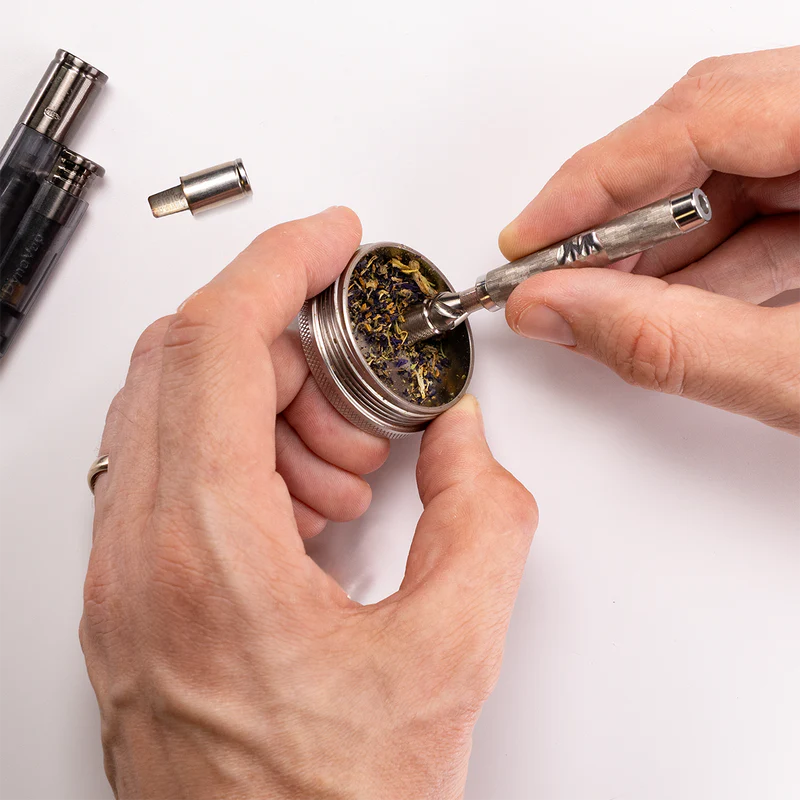 Long Lasting Dry Herb Vaporizers by DYNAVAP being used showing the herb being ground in a round stainless thing with a pointy stuff.