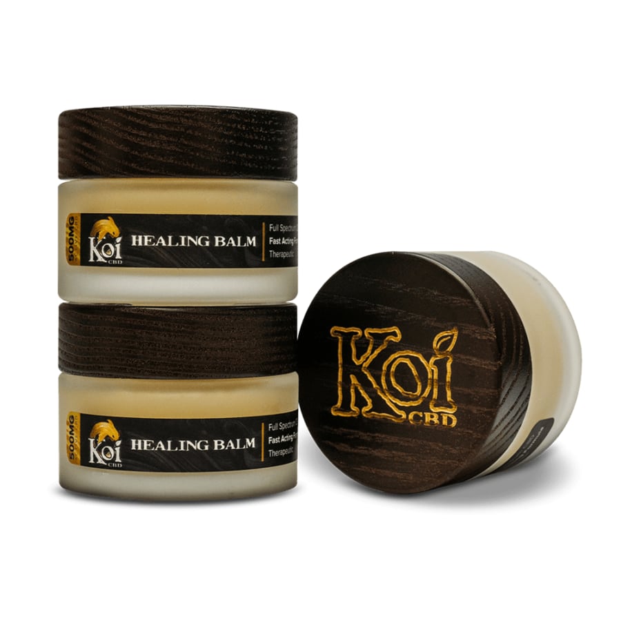 CBD balms from Koi showing three jars, one that is displayed sideways showing the black cover with "Koi" on it and two that are stacked on top of one another.